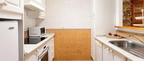 A compact kitchen with white cabinetry, a microwave, a toaster, and a sink.