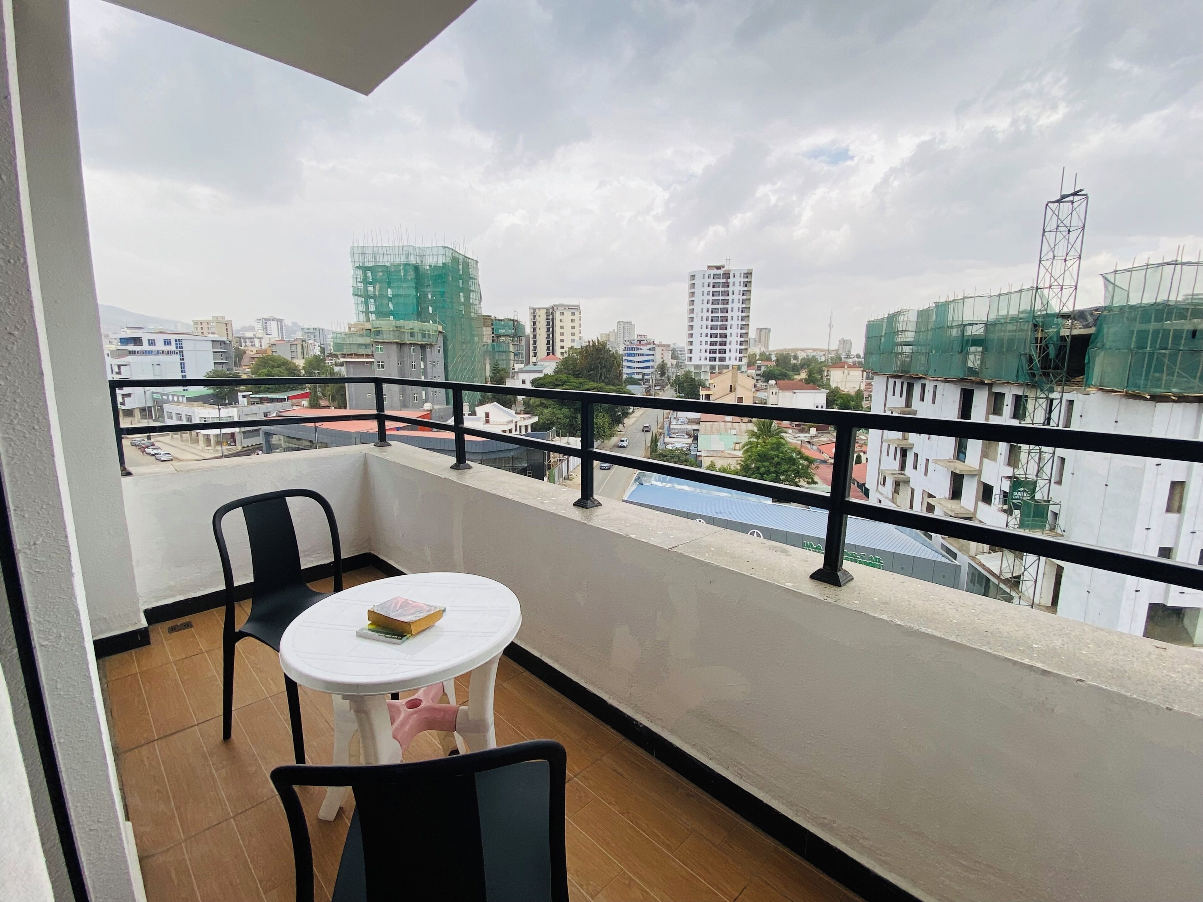 A balcony with a view of a cityscape, including buildings under construction and a clear sky.