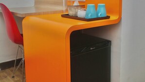 Un área de cocina compacta con un lavavajillas negro, una silla roja y una bandeja con tazas azules y una caja de pañuelos.