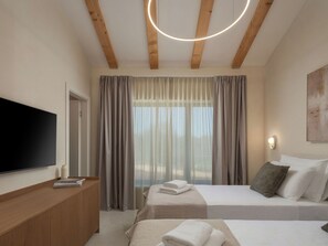 A hotel room with a flat-screen TV, a wooden desk, two beds with towels, a large window with curtains, and a ceiling light fixture. - Vacation home Nara by Interhome (Labin)