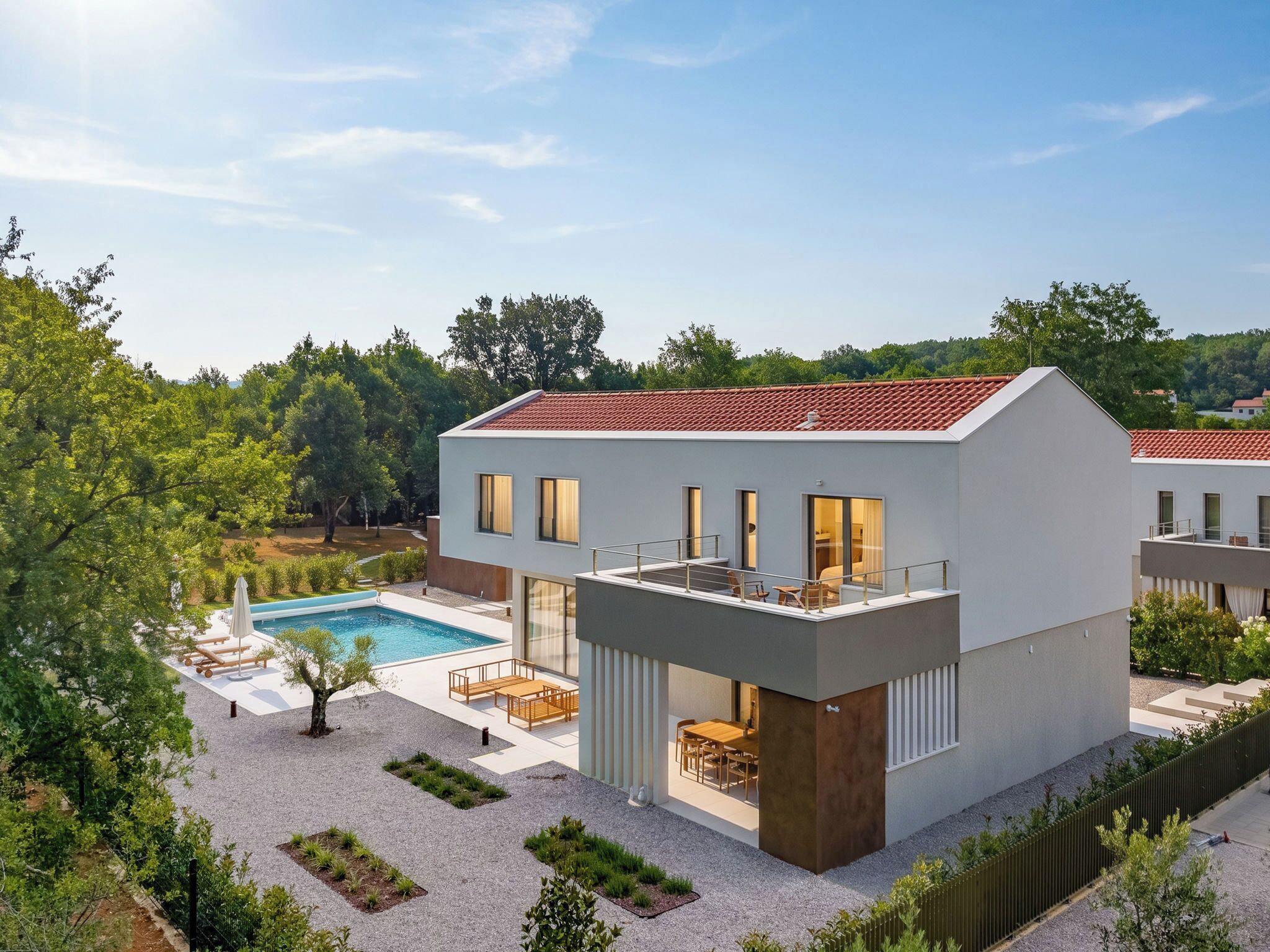 A modern two-story house with a swimming pool, outdoor seating, and a garden.