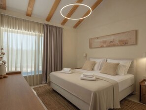 Ein Schlafzimmer mit einem Bett, einem Nachttisch, einer Lampe, einem Bild an der Wand und einem Fenster mit Vorhängen.