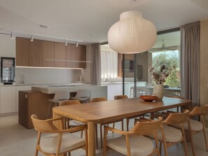 Eine moderne Küche mit Holzschränken, einer zentralen Kochinsel und einem Essbereich mit Holztisch und Stühlen.