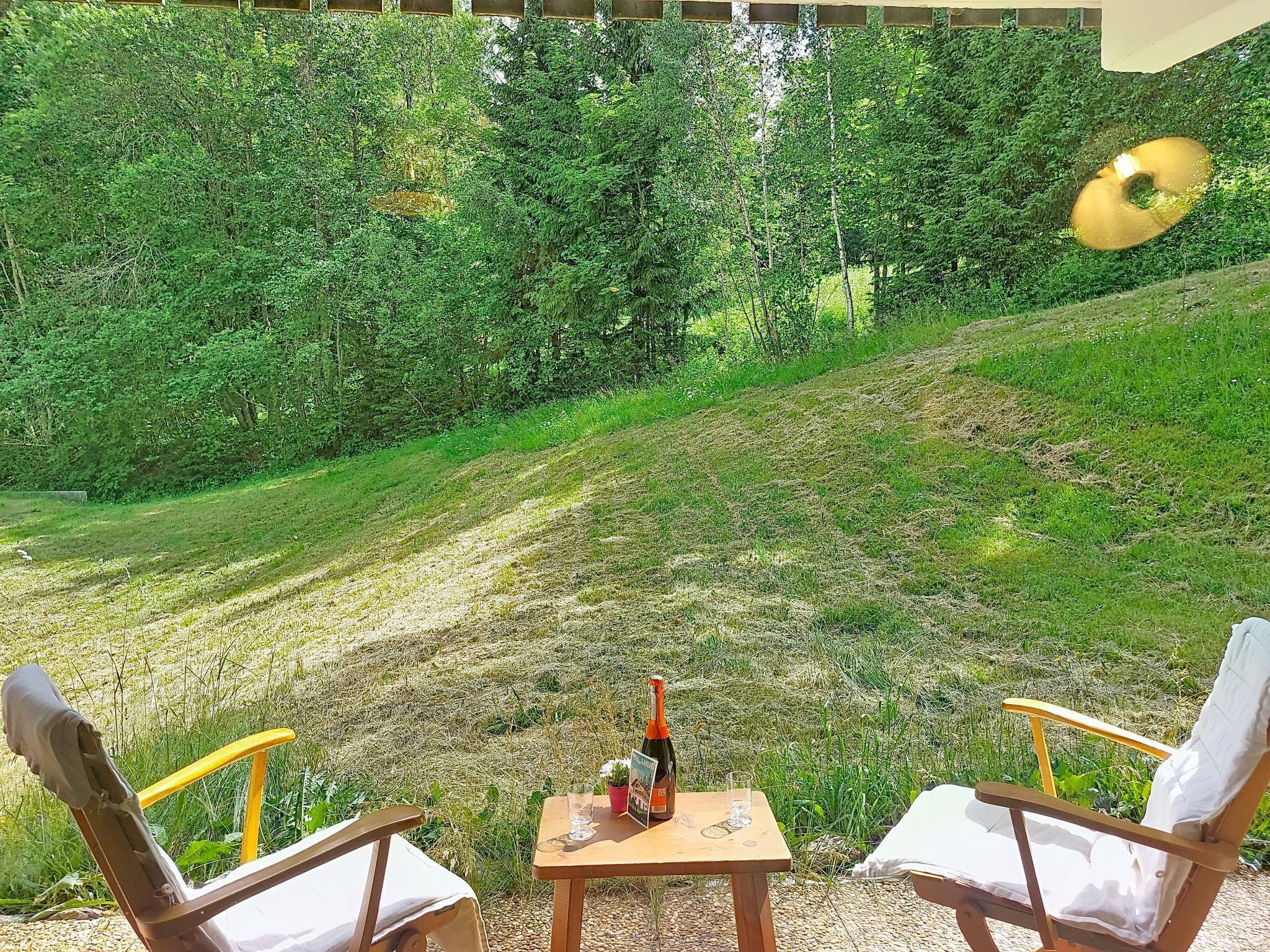 Ein Sitzbereich im Freien mit zwei Stühlen, einem Tisch und einer Weinflasche.