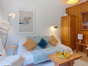 Ein gemütliches Zimmer mit einem Bett, einem Holzschrank, einem kleinen Tisch mit Tablett und einer Wandlampe.