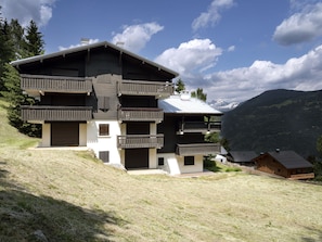 A multi-story chalet with balconies, a sloped roof, and a view of mountains. - Les Tétras by Interhome (Saint Gervais)