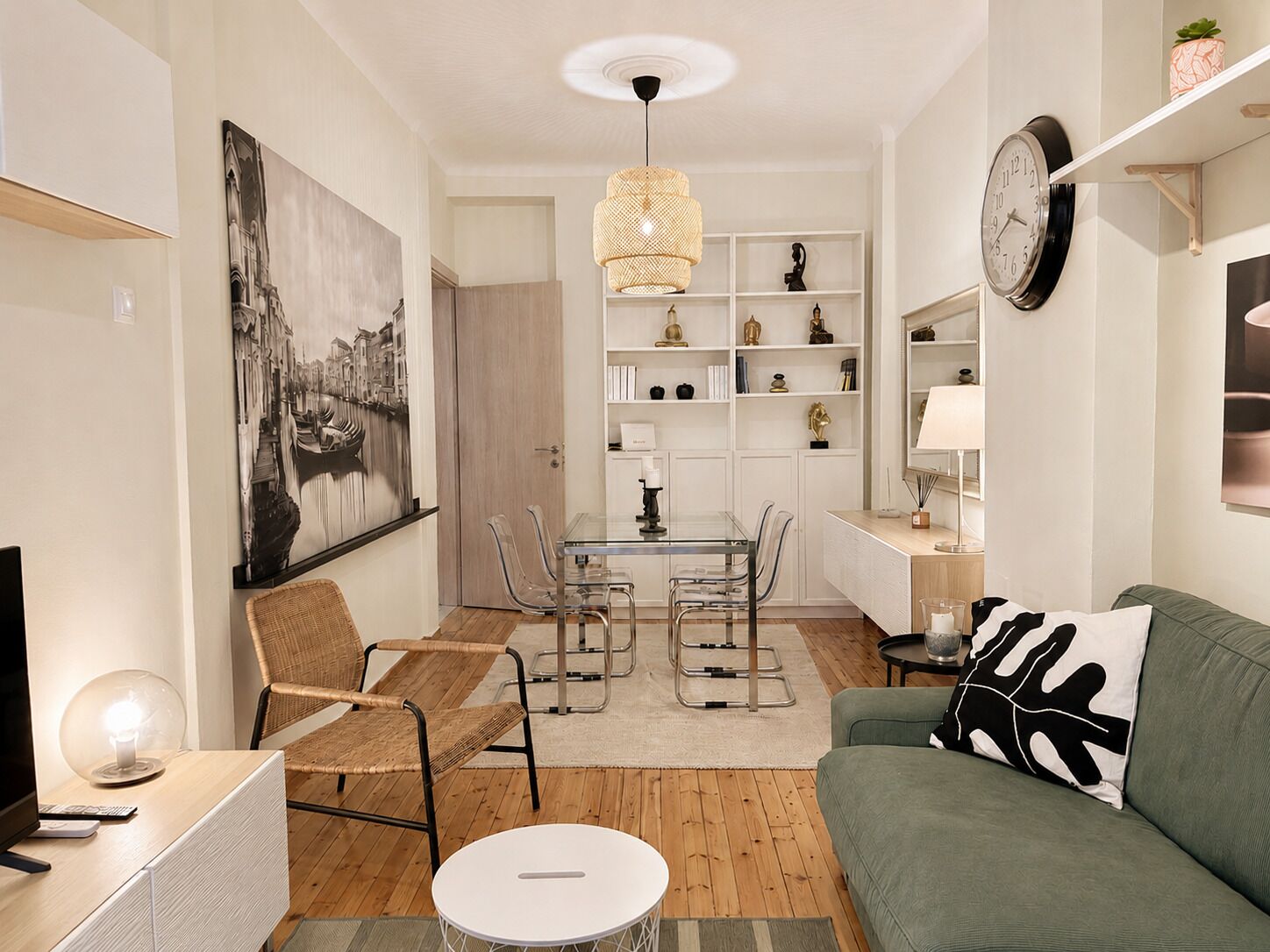 A modern living room with a dining area, a sofa, a TV, and a bookshelf.