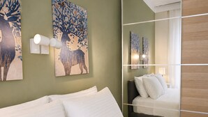 Ein Hotelzimmer mit einem Bett, Kunstwerken an den Wänden und einem Spiegel, der den Raum widerspiegelt.