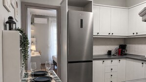 Eine moderne Küche mit weißen Schränken, einem Edelstahlkühlschrank und einem Essbereich mit Tisch für zwei Personen.