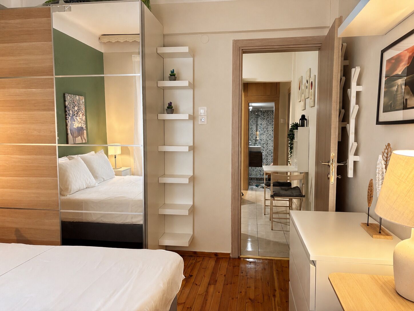 Une chambre d’hôtel équipée d’un lit, d’un bureau, d’une chaise, d’une lampe et d’une étagère ornée d’objets décoratifs.