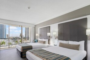 Ein Hotelzimmer mit zwei Betten, einem Balkon, Blick auf die Stadt und moderner Einrichtung.