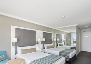 Ein Hotelzimmer mit zwei Betten, einem kleinen runden Tisch und einem Spiegel.