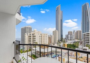 Ein Balkon mit Blick auf hohe Gebäude und einen Poolbereich.