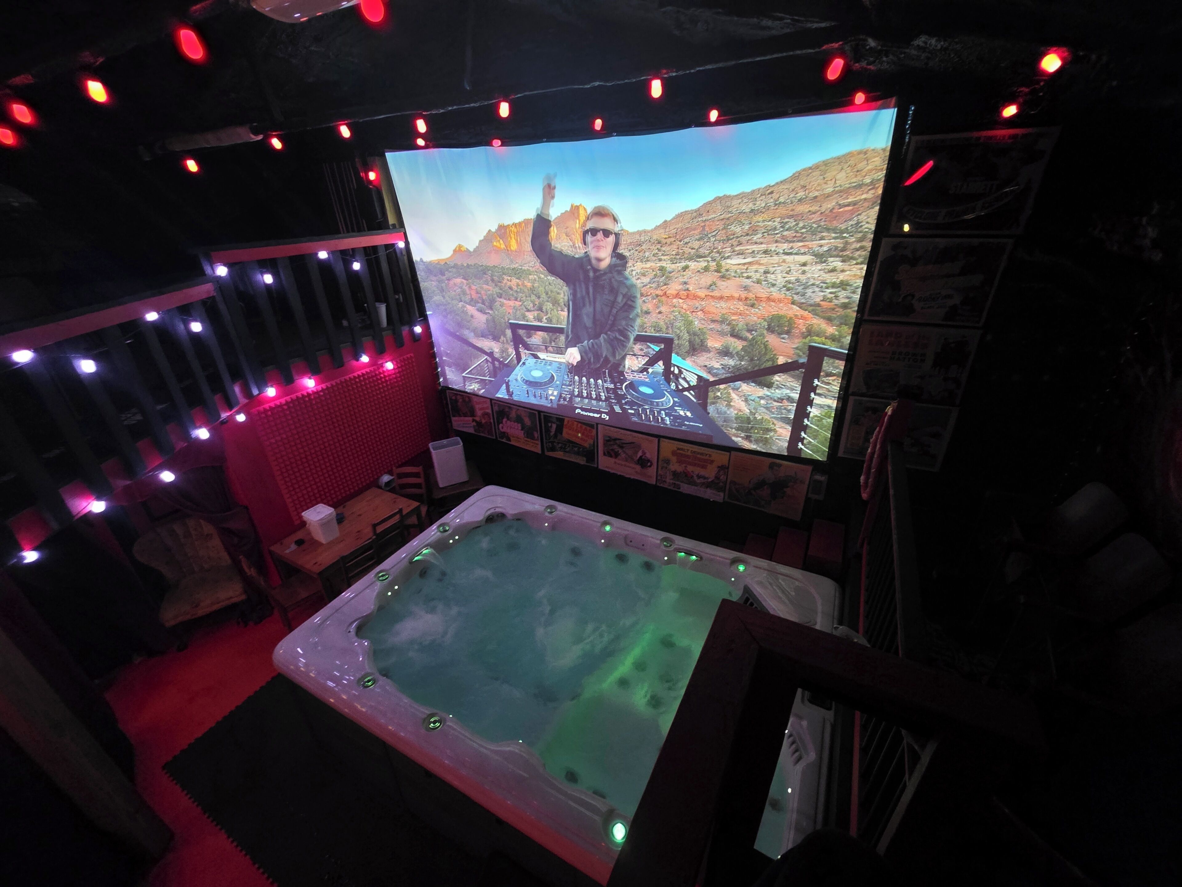 Een kamer met een groot scherm, een whirlpool en sfeerverlichting.