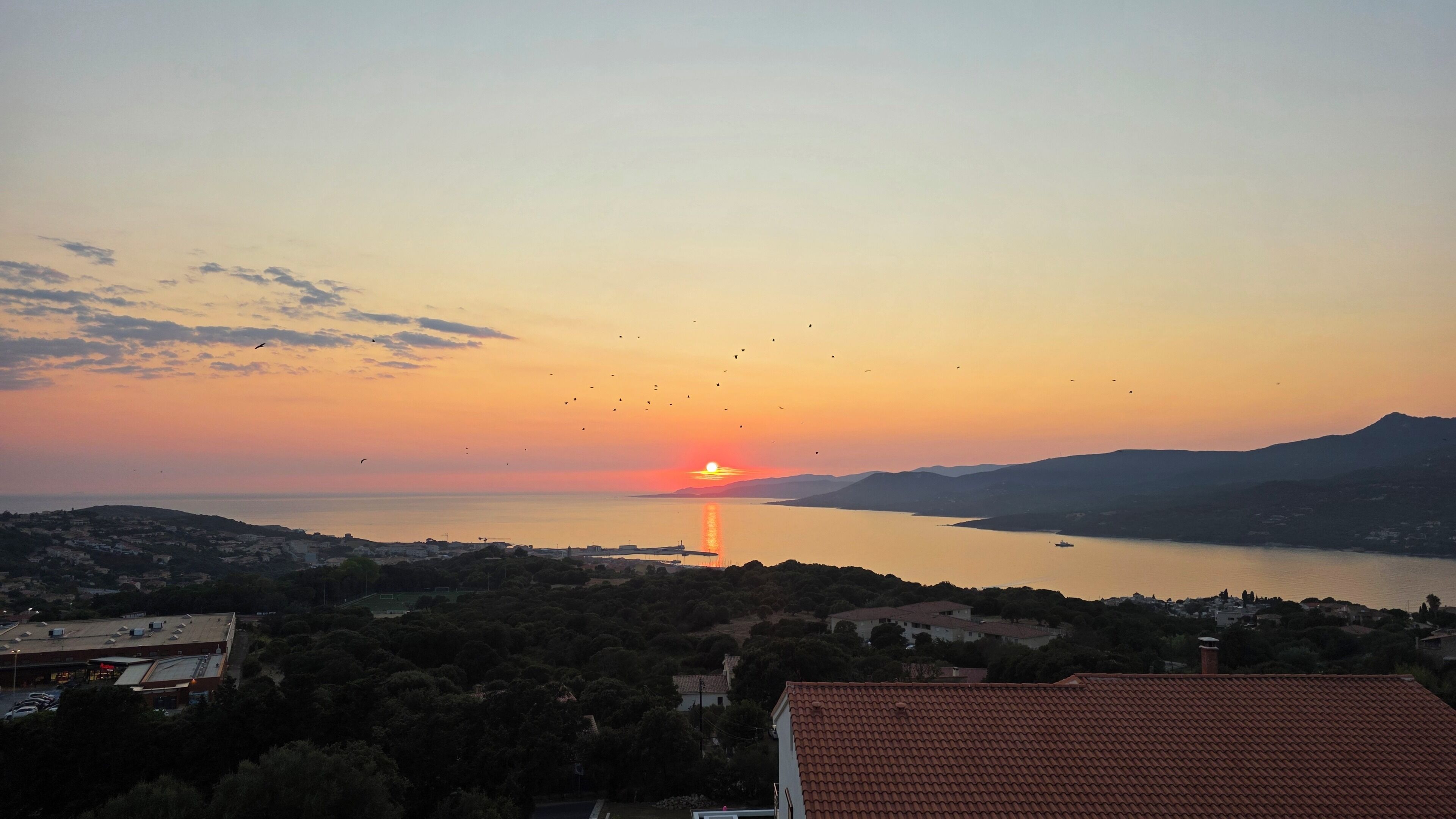 A sunset over a lake with buildings in the foreground.