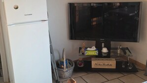 Eine Küchenzeile mit einem weißen Kühlschrank, einem Fernseher und einem Esstisch mit Stühlen.