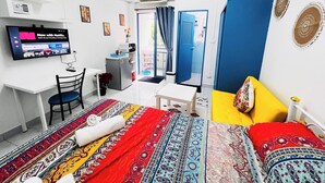 Ein Hotelzimmer mit einem Bett, einem Schreibtisch mit Computer, einem Fernseher und einem durch eine offene Tür einsehbaren Badezimmer.