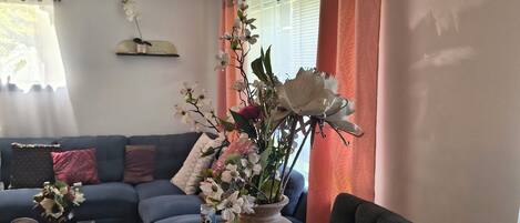 A dining table with a vase of flowers, a can of soda, and a book.