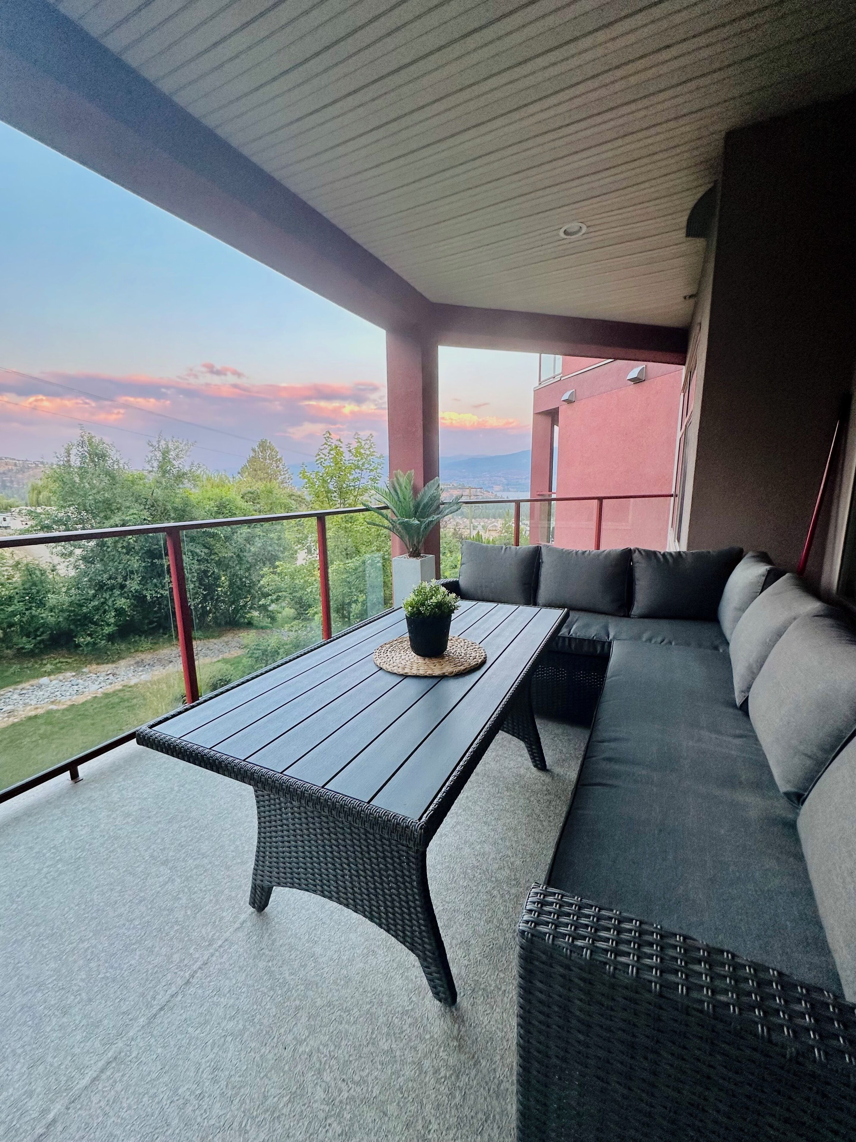 A balcony with a table and seating area, overlooking a scenic landscape.