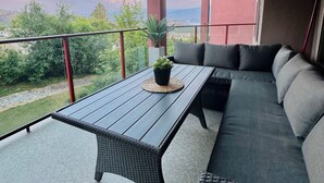 Un balcón con mesa y asientos, con vistas a un paisaje pintoresco.
