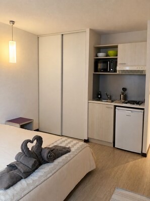 Ein Hotelzimmer mit Bett, einer kleinen Küchenzeile, einer Mikrowelle, einem Waschbecken und einem kompakten Kühlschrank.