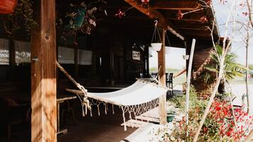 Une structure en bois avec un hamac, des plantes en pot et un mur de briques.