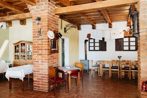 A rustic dining area with brick walls, wooden beams, a wooden cabinet, and a table with chairs.