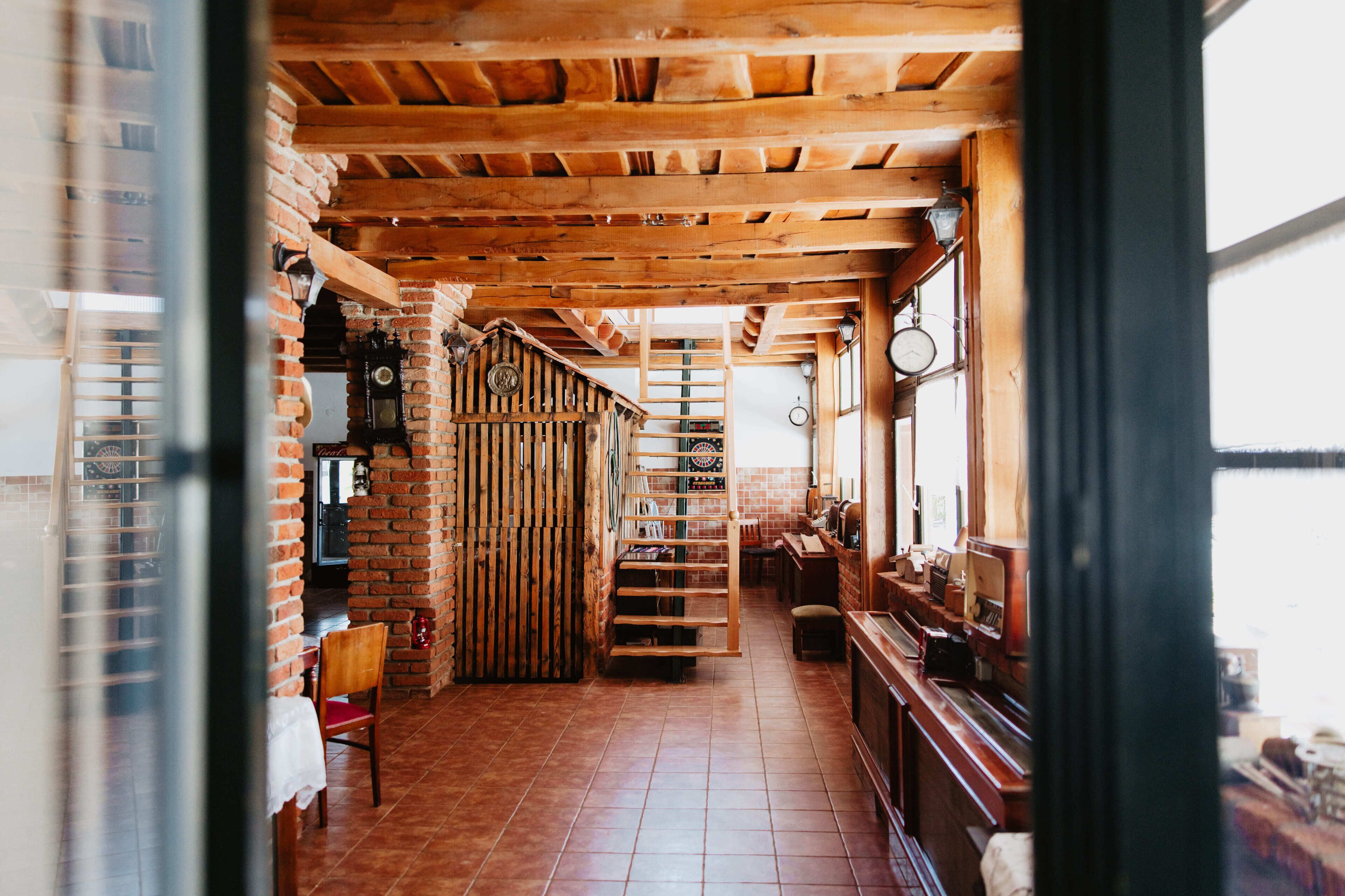 Un intérieur rustique avec des poutres apparentes, un mur en briques, un escalier et un piano.