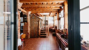 A rustic interior with exposed wooden beams, a brick wall, a staircase, and a piano.