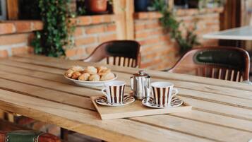 A wooden table with a tray of pastries, two cups, and a teapot.