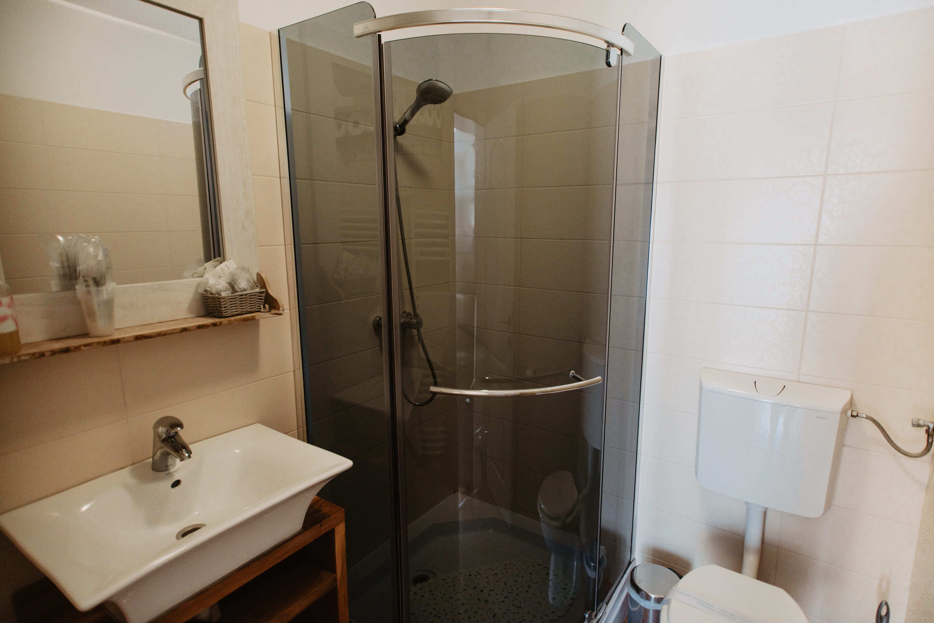 A bathroom with a glass-enclosed shower, a sink, and a toilet.
