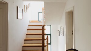 A staircase with wooden steps and a wooden handrail, leading to a door at the top.