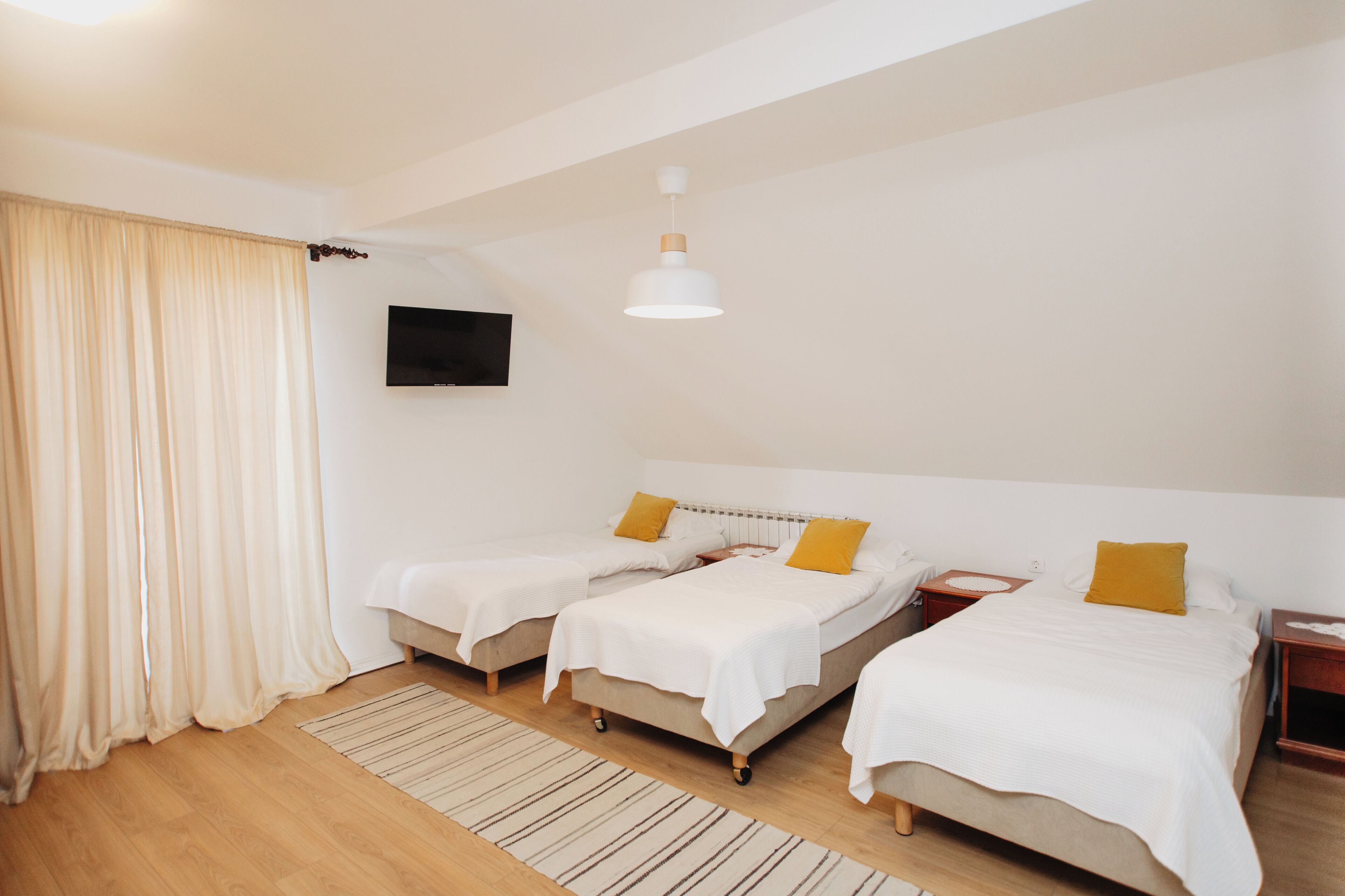 A hotel room with two beds, a TV, and a ceiling light.