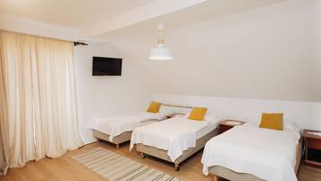 A hotel room with two beds, a TV, and a ceiling light.