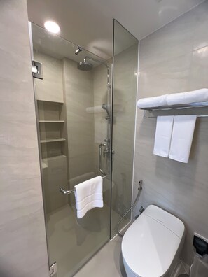 Un baño moderno con ducha de vidrio, inodoro blanco y toallero.