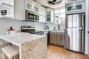 A modern kitchen with a marble island, stainless steel appliances, and a built-in oven. - Walk to the Beach! Quiet Resort Retreat in Maunabo (Maunabo)