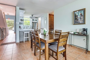 A dining area with a wooden table and chairs, a kitchen in the background, and a framed picture on the wall. - Walk to the Beach! Quiet Resort Retreat in Maunabo (Maunabo)