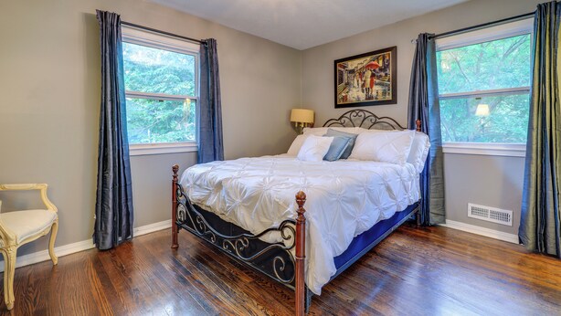 A bedroom with a bed, a chair, a window, and a painting on the wall. - 5 Mi to Kansas City Stadium! Bright Home w/ Yard (Kansas City)