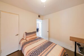 A bedroom with a bed, a desk, and a door leading to another room. - Duplex w/ Pet-Friendly Yard, 5 Mi to Dtwn Phoenix! (Phoenix)
