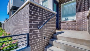 A modern building with a brick facade, a metal handrail, and concrete steps leading to a door. - Walk to Mile High Stadium: Denver Home w/ Deck (Denver)
