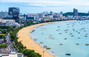 Eine Küstenstadtlandschaft mit einem weiten Sandstrand, zahlreichen Booten und einer dichten Skyline im Hintergrund.