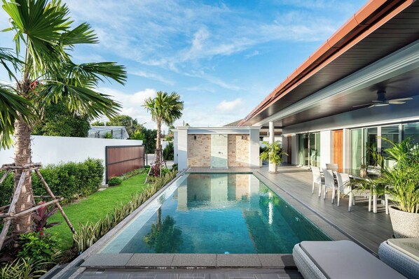 A modern house with a swimming pool, outdoor furniture, and a well-maintained garden.