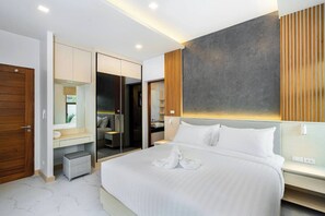 A modern hotel room with a large bed, a walk-in closet, a bathroom with a glass shower, and a view of the outdoors.