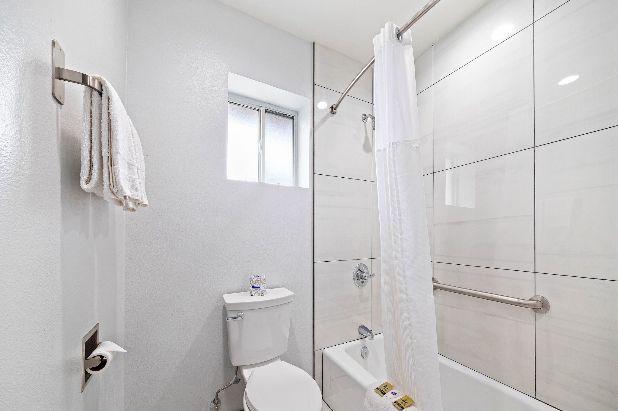 A bathroom with a toilet, a shower with a glass door, and a towel rack.