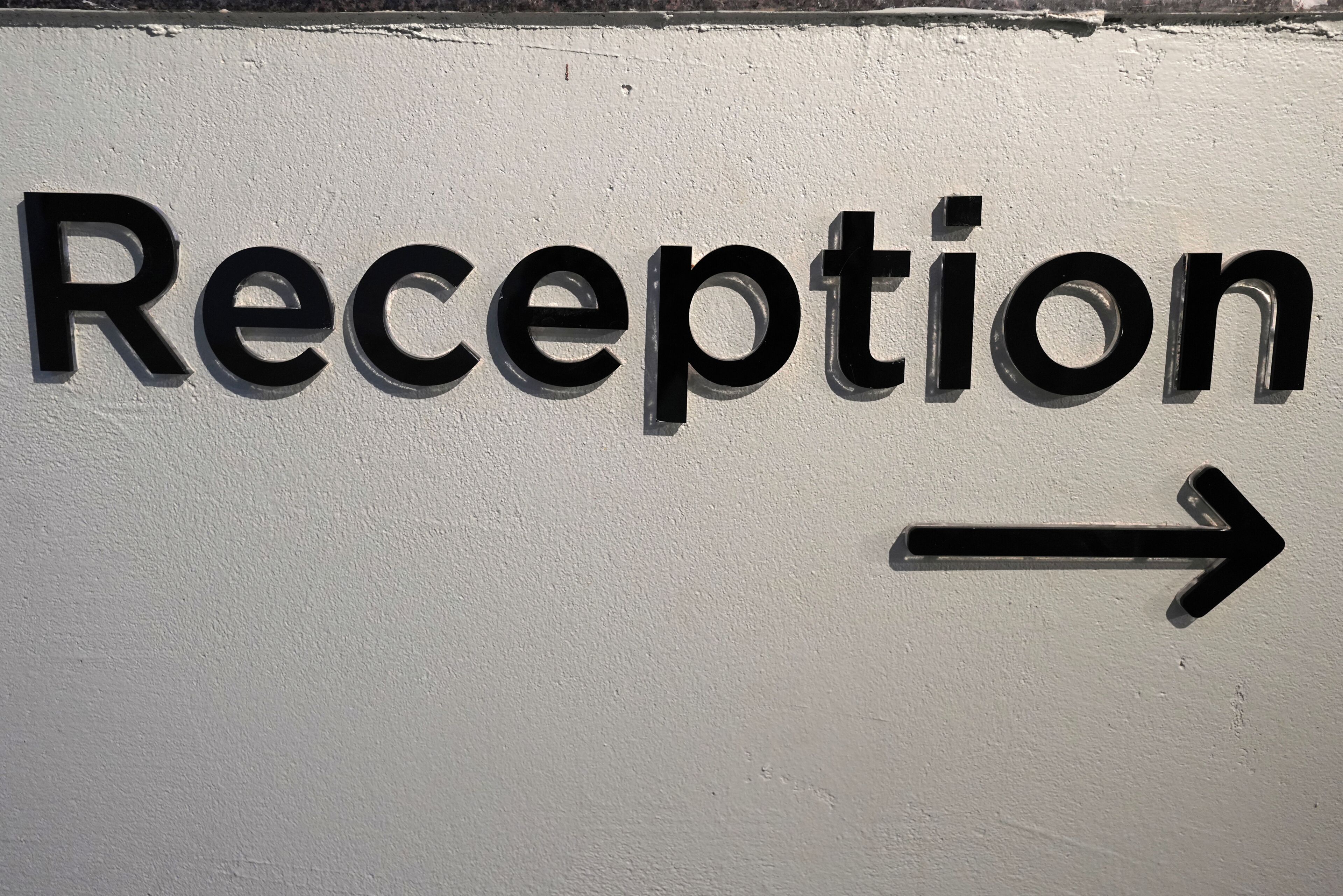 Segnaletica con la scritta 'Reception' e una freccia che indica a destra.