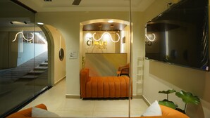 A hotel reception area with a sofa, a TV, and a ceiling fan.