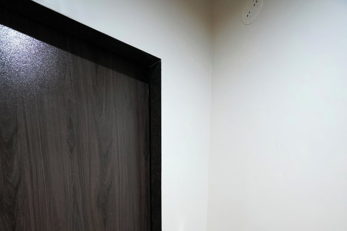 Una puerta de madera oscura, un estante con una tetera, tazas y toallas.