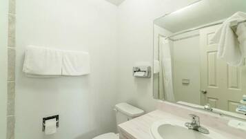 Un baño con inodoro, lavamanos, espejo y perchero para toallas.