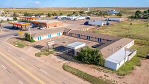 A motel with a gas station, a parking lot, and a small building with a sign.