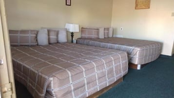 Quarto de hotel com duas camas, uma mesa de cabeceira, um abajur e um quadro na parede.